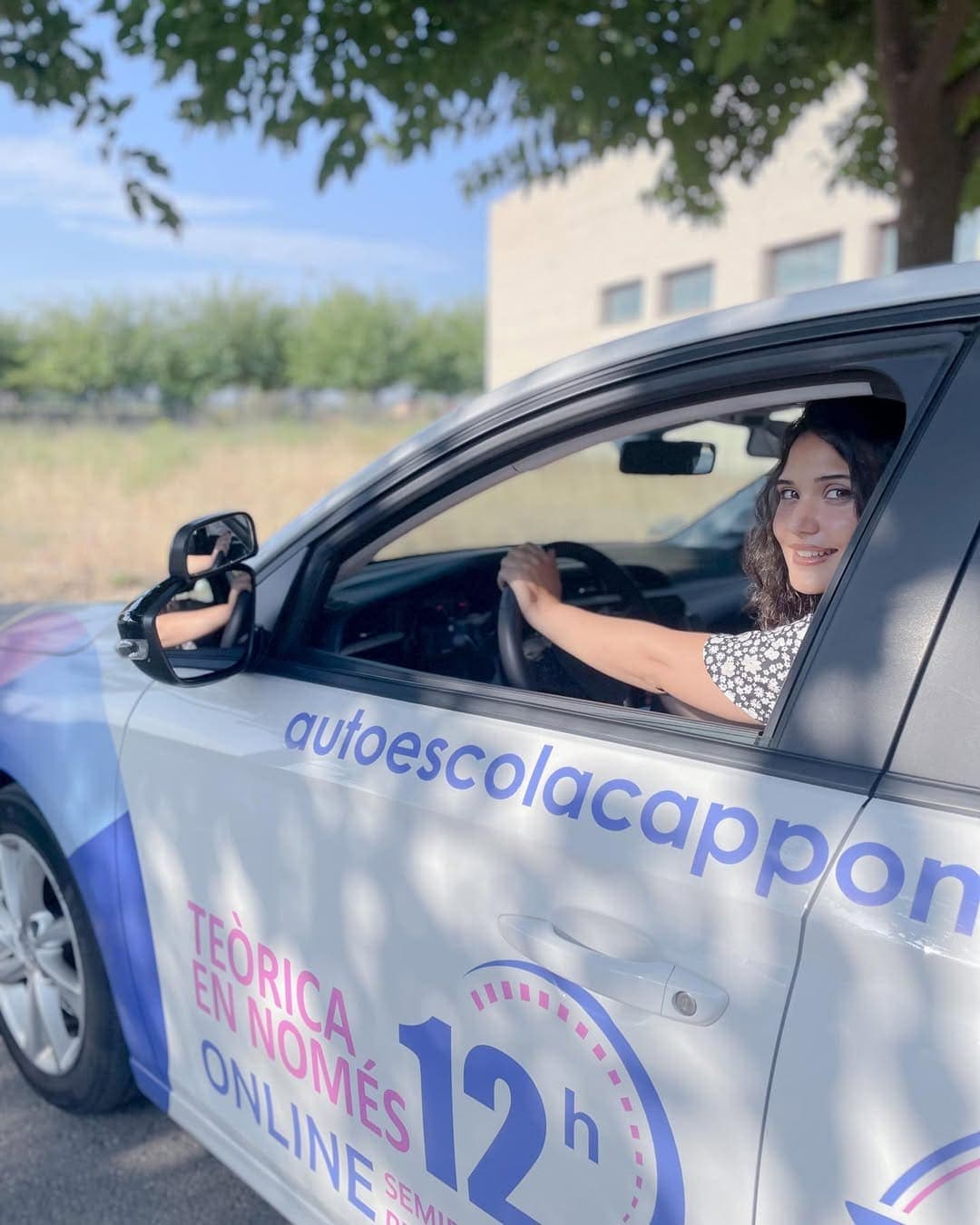 Una alumna somrient al volant d’un cotxe de l’autoescola.