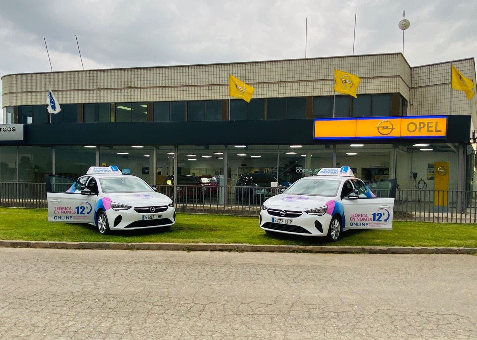 Dos cotxes de pràctiques de Cappont Mobilitat davant d’un concessionari.