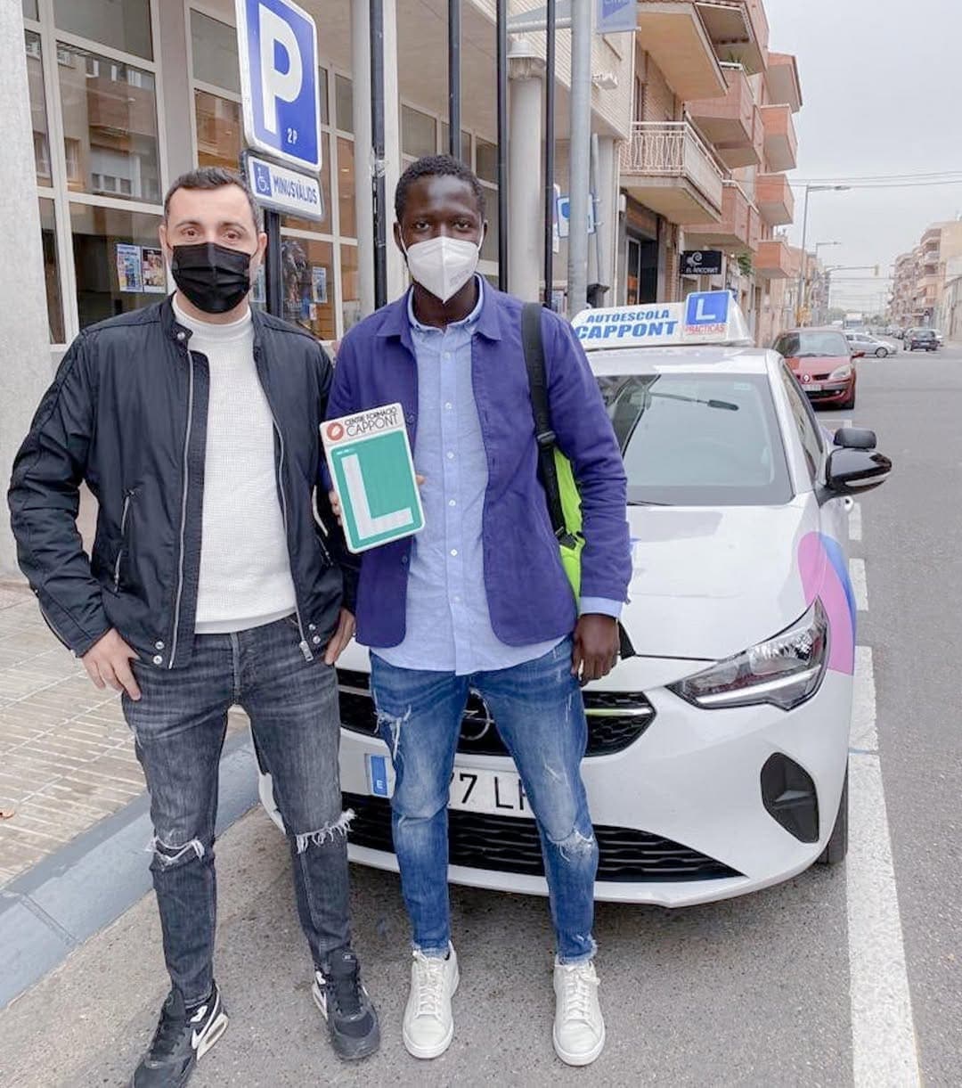 Un alumne amb la placa L acabat d’aprovar, amb el seu professor.