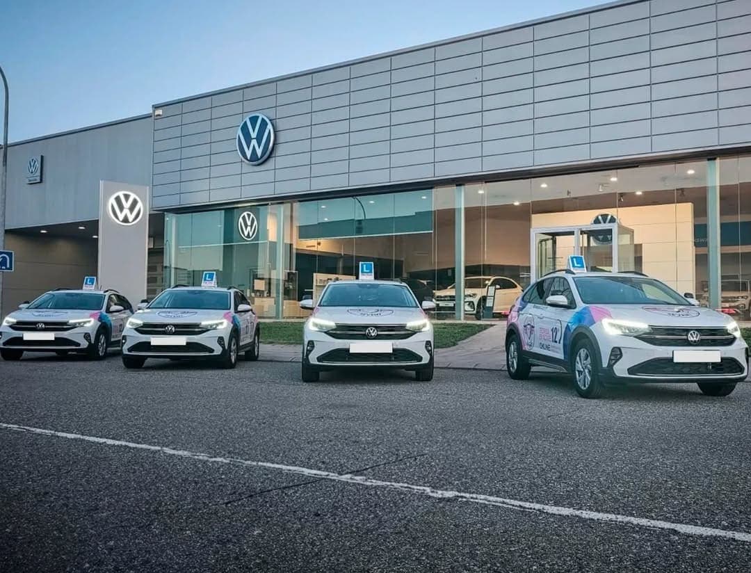 The fleet of practice cars outside a car dealership.